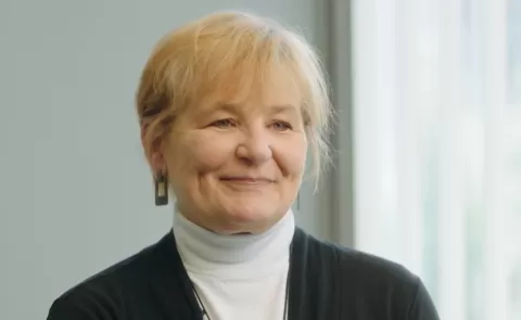 Joanne, a smiling woman with short hair wearing a turtleneck and sweater