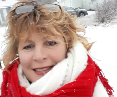 Smiling woman in winter clothes with snow in the background