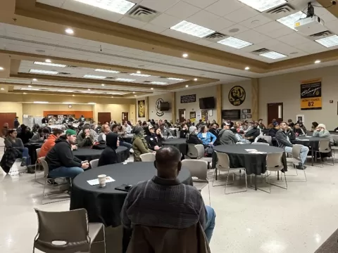 large crowd of people sitting at tables in large meeting room