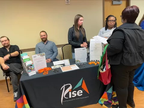 picture of staff at tables and a customer at a career fair