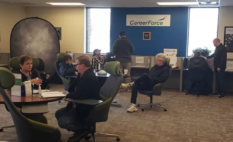 people sitting and standing and talking in a large room with CareerForce signage