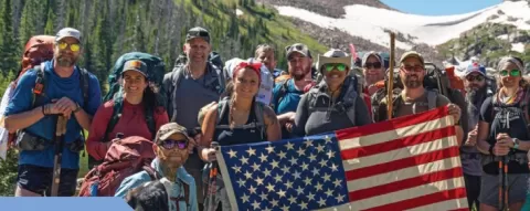 group of smiling people outdoors holding an American flag