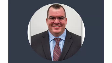 smiling man wearing glasses and a suit and tie