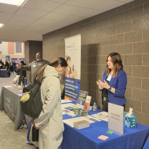 people talking at a display table with CareerForce information