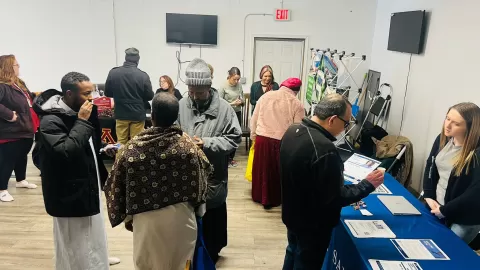 crowds of people talking with other people at display tables in a large room