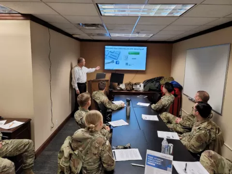 people in military uniform in a conference room looking at a person presenting workshop materials on screen