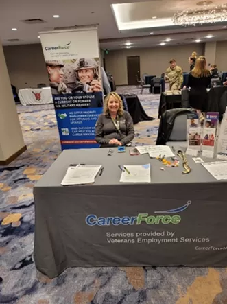 Jane Kerntz, a person sitting at display table with CareerForce banner