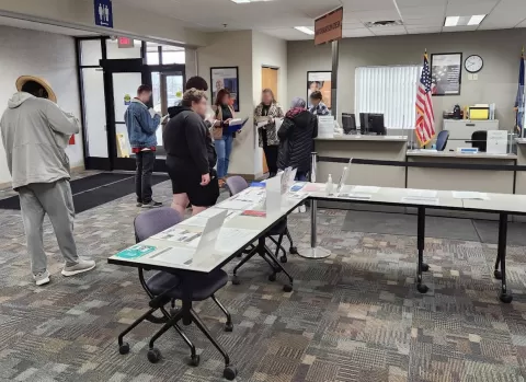 people in a room with a table and information desk style counter