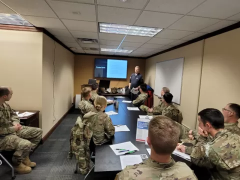 people in military uniform in a conference room looking at a person presenting workshop materials on screen