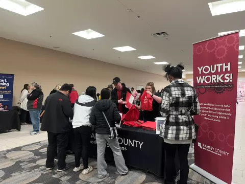 many people standing in a large room filled with tables with brochures and other resources