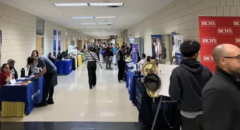 a long hallway lined with tables with many people standing and walking around