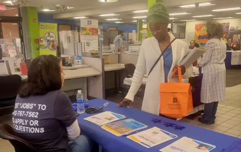 people standing and sitting at display tables with promotional materials on them
