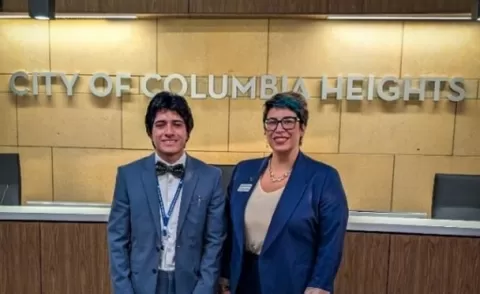 two people wearing suit jackets standing in front of a sign that says City of Columbia Heights
