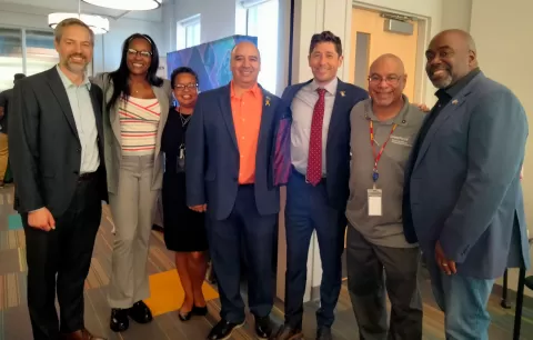seven people in business clothing standing together smiling at the camera