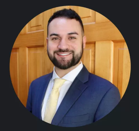 smiling person wearing a shirt and suit jacket