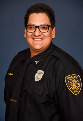 smiling person in a firefighters uniform wearing a badge