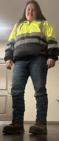 person wearing reflective jacket, jeans and work boots