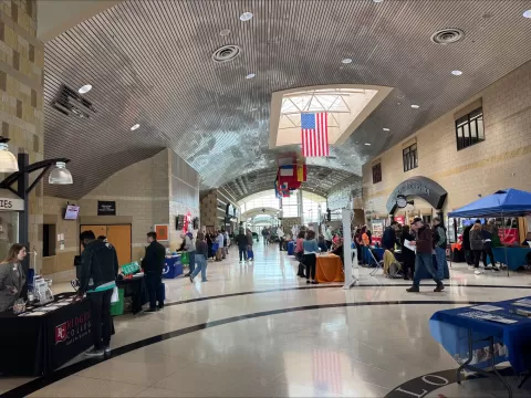 many people in a very large room with tables lining the walls