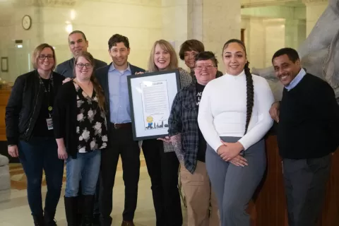 photo of nine people, one of the people is holding a framed certificate