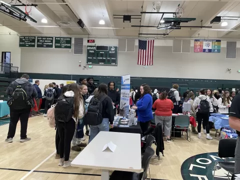 many people standing in a large room with display tables