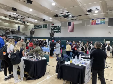 many people standing in a large room with display tables