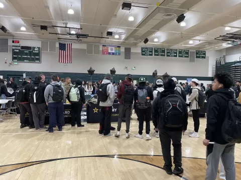 many people in a very large room with tables holding display materials