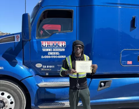 a person holding a certificate standing in front of a semi-truck
