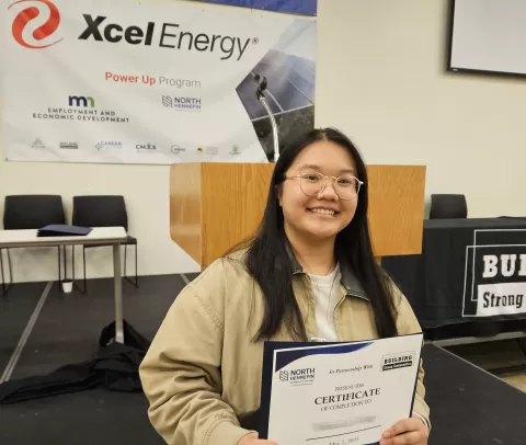 photo of smiling person wearing glasses holding a certificate