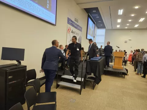 two people shaking hands in a large room with a stage