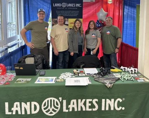group of people standing behind a table with a Land O' Lakes table skirt