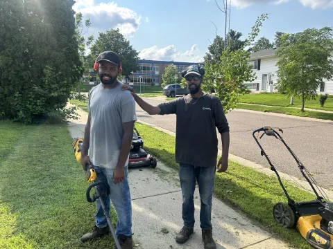 two people standing together outside with lawn care equipment