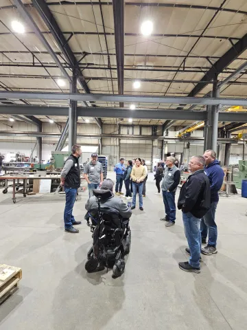 several people standing and one person in a wheelchair in a very large building