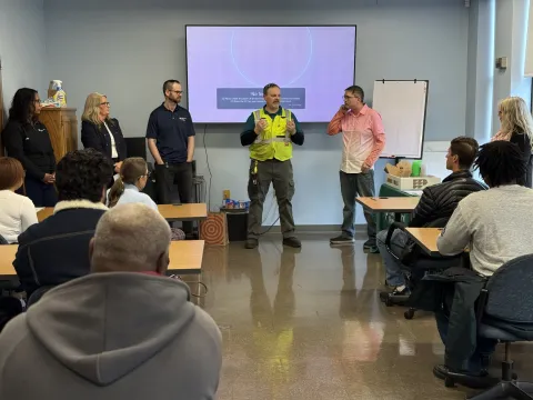people standing at the front of a large room presenting to people in chairs