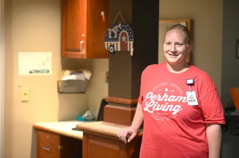 smiling person wearing red perham living shirt 