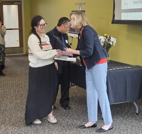 Smiling person shaking another person's hand, Mue Hsae at semiconductor manufacturing program graduation June 2025