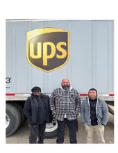 people standing in front of a UPS heavy truck and trailer