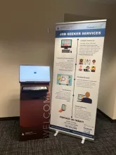a computer monitor and keyboard on a stand next to a banner that says job seeker services with a CareerForce logo