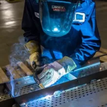 person in a helmet and other protective gear welding 