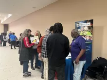 people standing around a table with a banner behind it that reads Minnesota Department of Labor and Industry