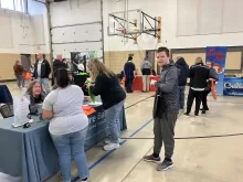 many people in a gymnasium with tables lining the walls