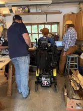 photo of four people in a woodshop with one person in a wheelchair